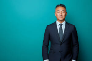 Middle aged Asian man wearing a dark suit and tie, projecting professionalism, confidence, and experience
